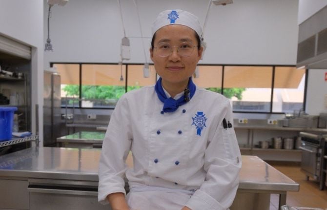 chef in a white uniform with a plate of food